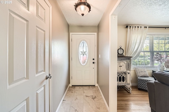 entryway featuring baseboards, a textured ceiling, and marble finish floor