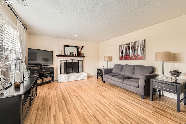 living area featuring a textured ceiling, light wood finished floors, and a fireplace