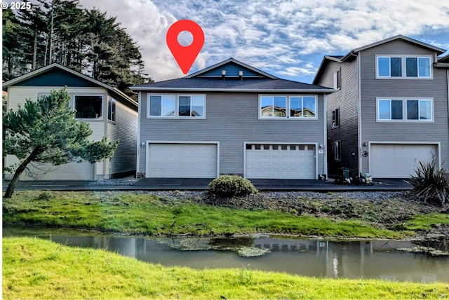 29027 Vizcaino Ct, Gold Beach, OR 97444 - view of front of house featuring an attached garage, asphalt driveway, and a water view