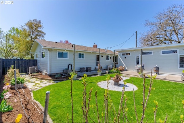 back of property with central AC unit, fence, a yard, a patio, and an outdoor fire pit