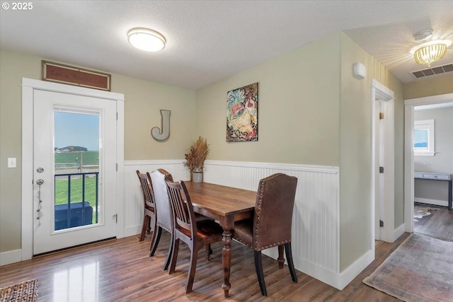dining area featuring wainscoting, a wealth of natural light, and wood finished floors