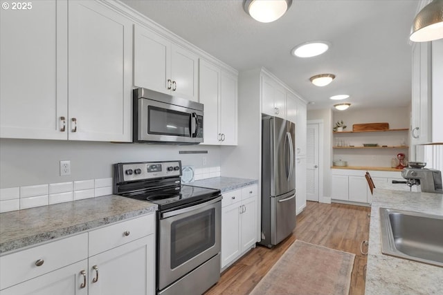 kitchen with light wood finished floors, light countertops, white cabinetry, and appliances with stainless steel finishes