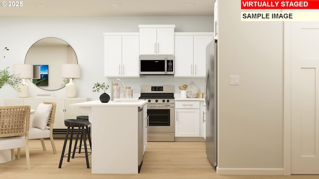 kitchen with stainless steel appliances, light wood-type flooring, white cabinets, and a kitchen breakfast bar