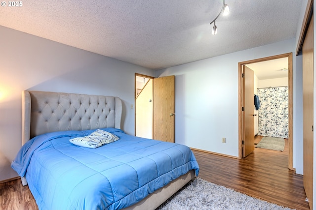 bedroom featuring hardwood / wood-style floors, track lighting, and a textured ceiling