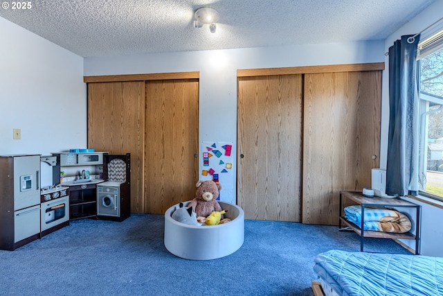 playroom with a textured ceiling and dark colored carpet