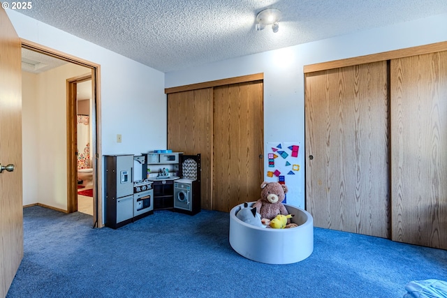 playroom featuring dark carpet and a textured ceiling