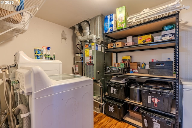 clothes washing area with hardwood / wood-style flooring and washer and dryer