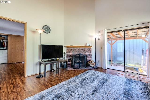 living room featuring dark hardwood / wood-style floors, a brick fireplace, and a high ceiling