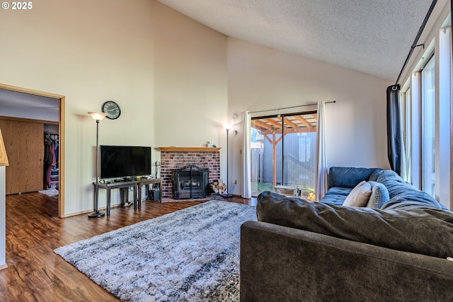 living room with high vaulted ceiling, dark hardwood / wood-style floors, a textured ceiling, and a fireplace