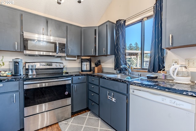 kitchen with sink, gray cabinets, appliances with stainless steel finishes, light hardwood / wood-style floors, and a textured ceiling