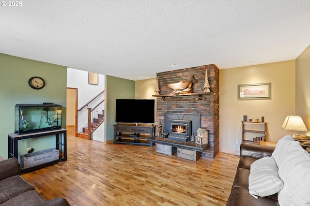 living room with hardwood / wood-style flooring, a brick fireplace, and a textured ceiling