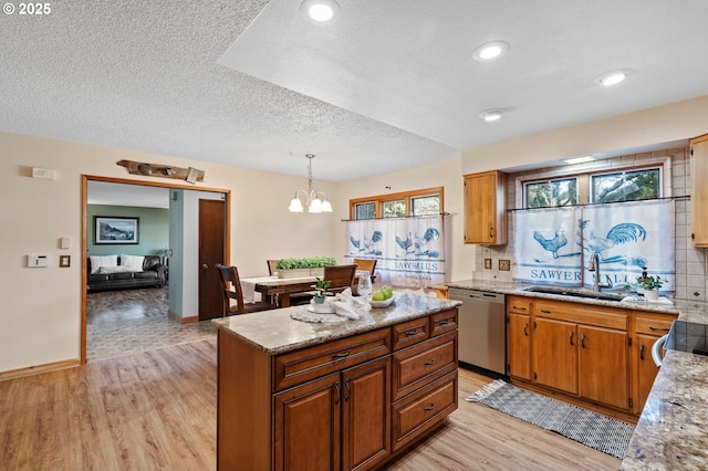 kitchen featuring sink, dishwasher, a center island, decorative light fixtures, and light wood-type flooring