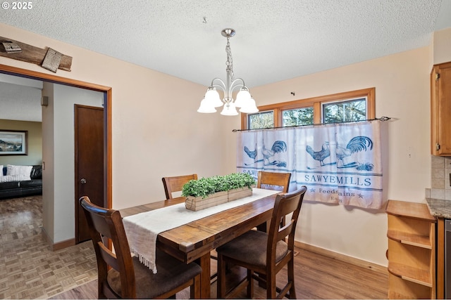 dining room with a notable chandelier, a textured ceiling, and light hardwood / wood-style flooring