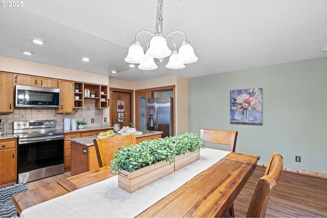 dining space with light hardwood / wood-style floors, a textured ceiling, and a notable chandelier