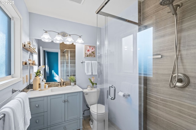 bathroom with vanity, a wealth of natural light, toilet, and a shower with shower door