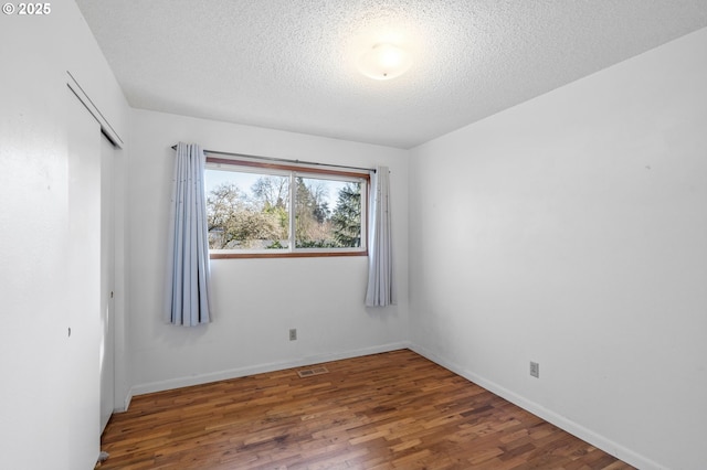 empty room featuring dark wood-type flooring and a textured ceiling