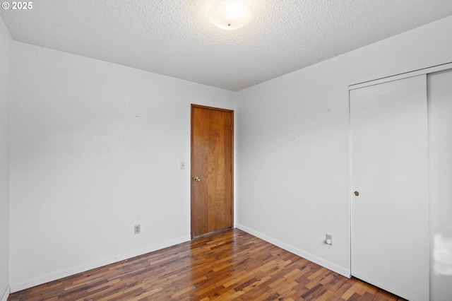 unfurnished bedroom featuring dark wood-type flooring, a closet, and a textured ceiling