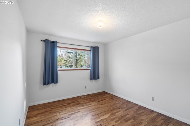 spare room featuring hardwood / wood-style flooring and a textured ceiling