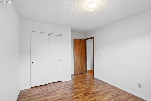 unfurnished bedroom with a textured ceiling, light hardwood / wood-style floors, and a closet