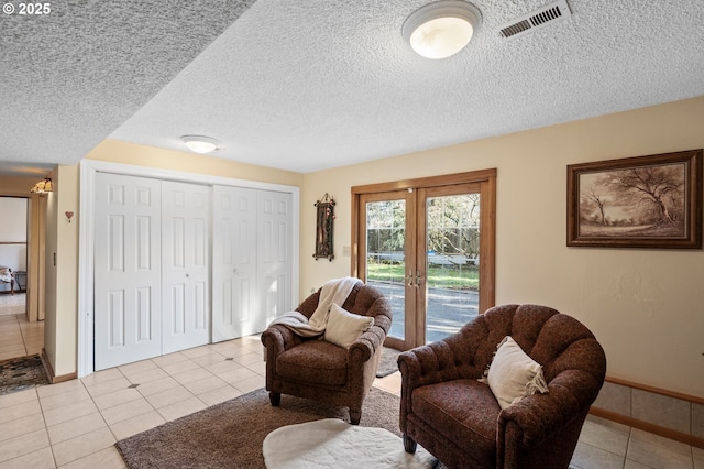 sitting room with light tile patterned floors, a textured ceiling, and french doors