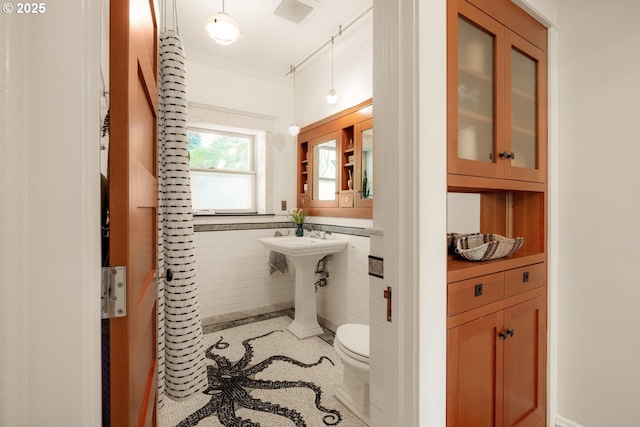 bathroom with crown molding, tile walls, toilet, and visible vents