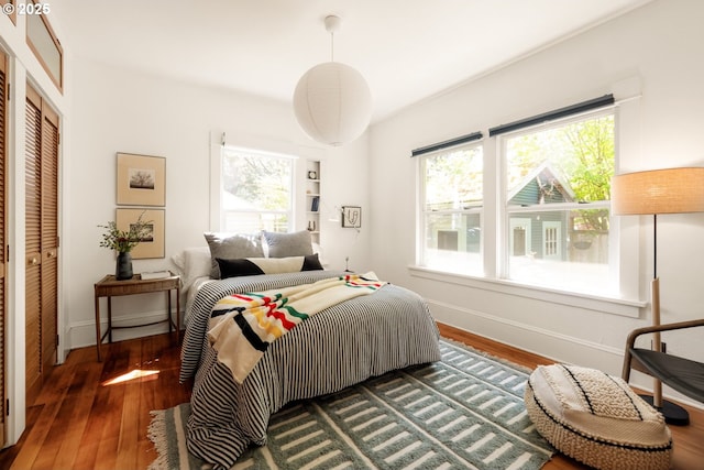 bedroom featuring wood-type flooring, baseboards, and a closet