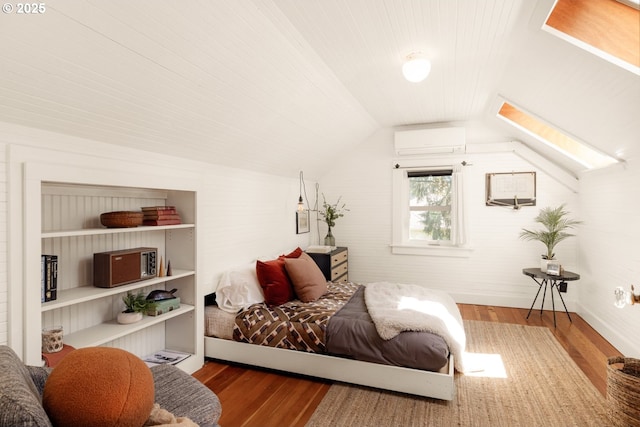 bedroom featuring wood finished floors, lofted ceiling with skylight, and a wall unit AC