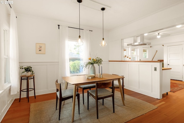 dining space with ornamental molding, light wood finished floors, and a decorative wall