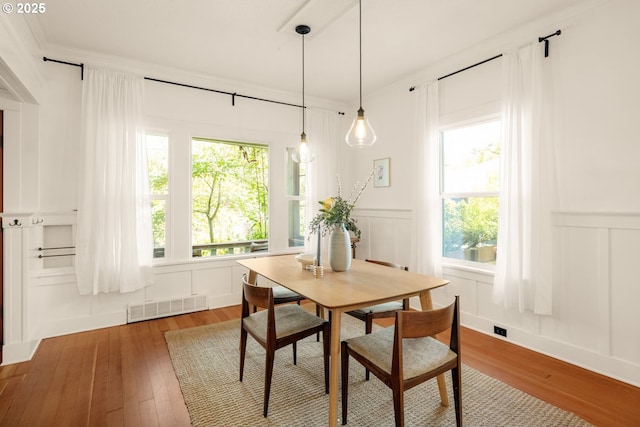dining room with visible vents, crown molding, wainscoting, a decorative wall, and hardwood / wood-style floors