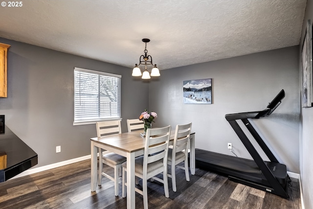 dining room with dark wood-style floors, a textured ceiling, a chandelier, and baseboards