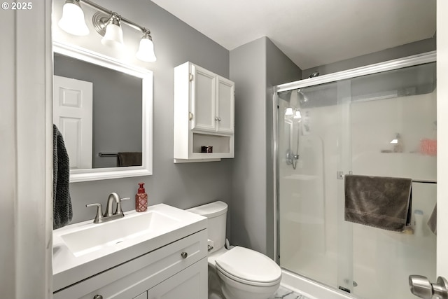 full bathroom featuring a stall shower, vanity, and toilet