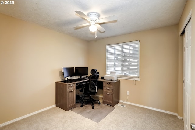 home office with a ceiling fan, light colored carpet, and baseboards