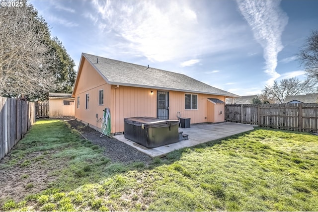 back of property featuring a hot tub, a shingled roof, a lawn, a fenced backyard, and a patio area