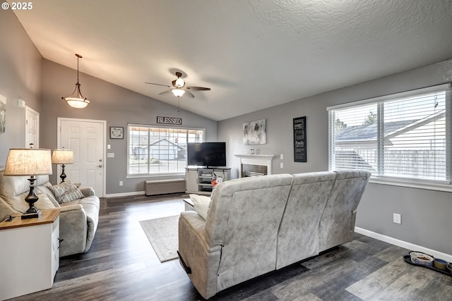 living area featuring dark wood-style flooring, a fireplace, a ceiling fan, baseboards, and vaulted ceiling