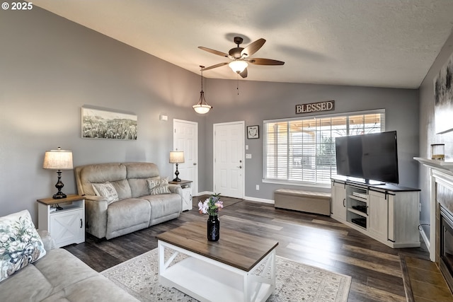 living area with lofted ceiling, dark wood-style floors, ceiling fan, and baseboards