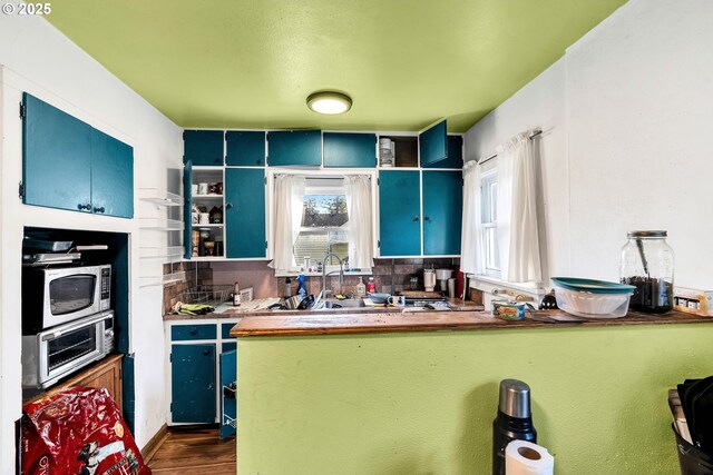 12107 SE Carlton St, Portland, OR 97266 - kitchen with stainless steel microwave, blue cabinetry, open shelves, and dark wood-style floors