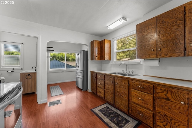 4529 SE 44th Ave, Portland, OR 97206 - kitchen featuring appliances with stainless steel finishes, dark wood-style flooring, arched walkways, and healthy amount of natural light