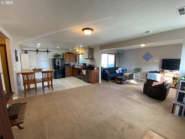 living room with a textured ceiling, a barn door, recessed lighting, light carpet, and visible vents