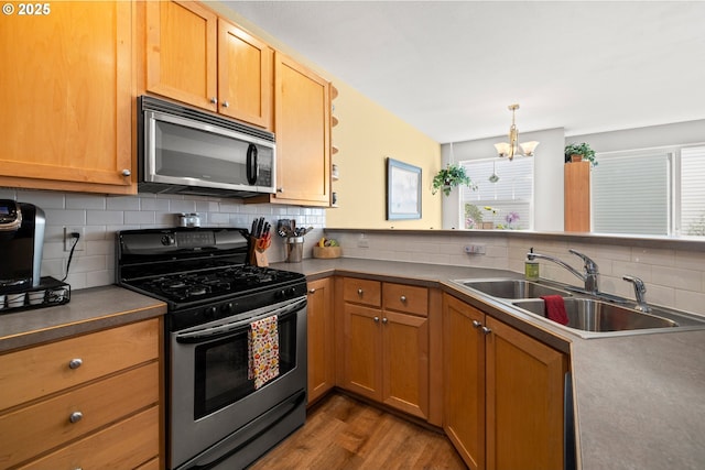 14640 SW Redbud Way, Beaverton, OR 97007 - kitchen featuring appliances with stainless steel finishes, a chandelier, wood finished floors, tasteful backsplash, and brown cabinets