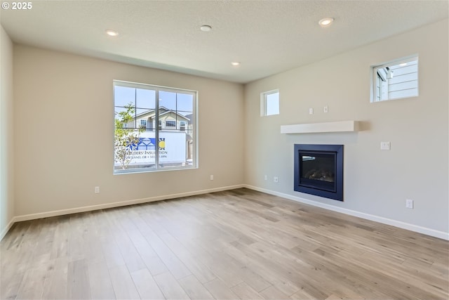 31709 NW Turel Dr, North Plains, OR 97133 - unfurnished living room featuring recessed lighting, baseboards, a glass covered fireplace, and light wood finished floors