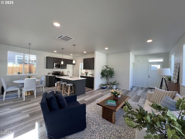 living room with light wood-style floors, recessed lighting, and a chandelier