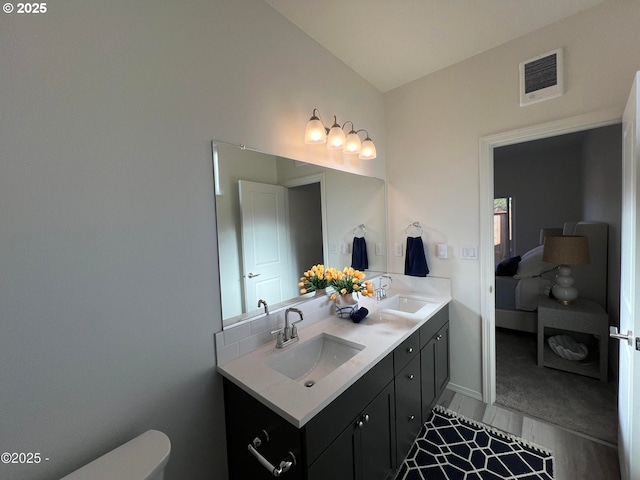bathroom featuring double vanity, wood finished floors, baseboards, and toilet
