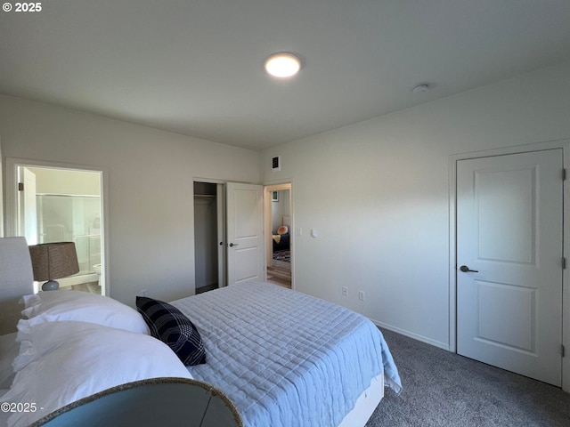bedroom featuring dark colored carpet, ensuite bathroom, baseboards, and a closet