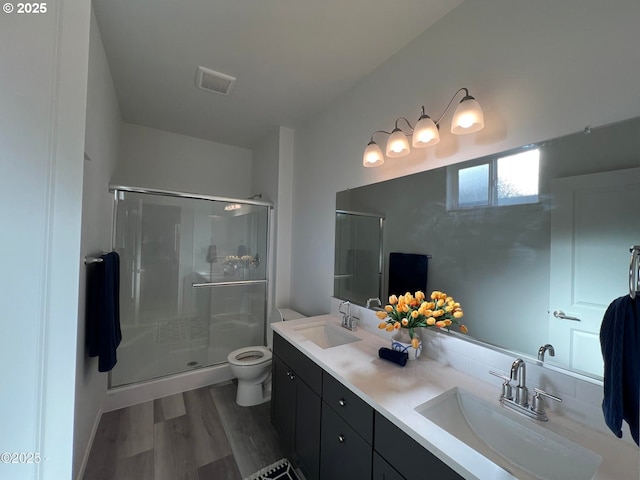 full bathroom with a shower stall, toilet, double vanity, and wood finished floors