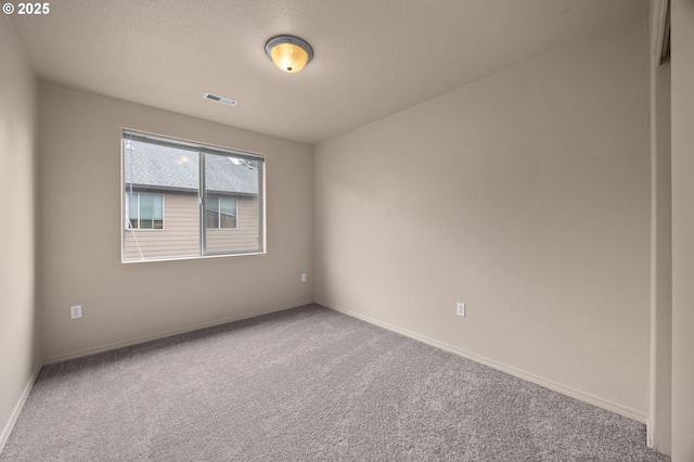 carpeted spare room with visible vents, baseboards, and a textured ceiling