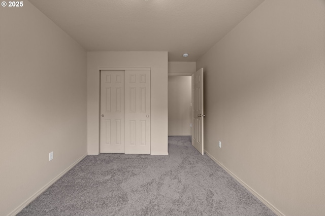 unfurnished bedroom featuring carpet floors, a closet, and baseboards