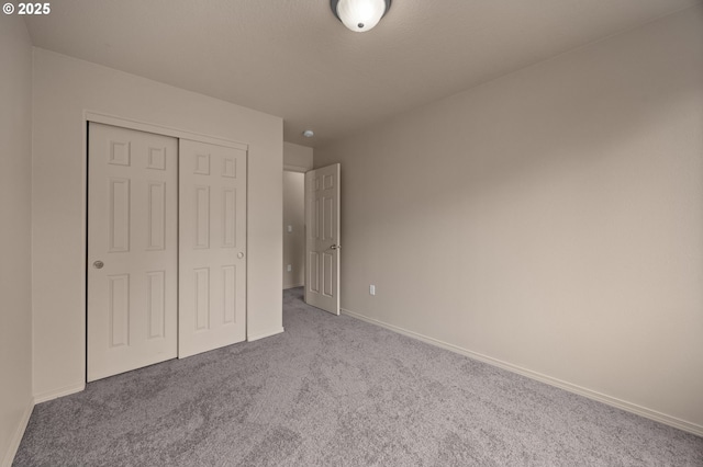 unfurnished bedroom with carpet floors, a closet, and baseboards