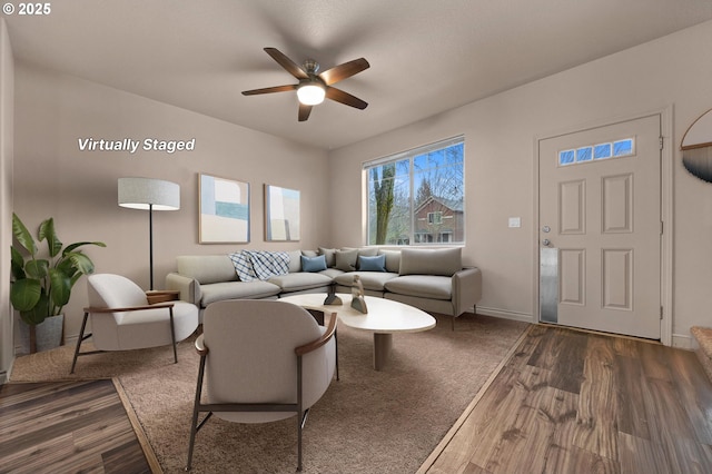 living area featuring baseboards, a ceiling fan, and wood finished floors