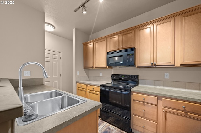 kitchen with black appliances, wood finished floors, a sink, and light countertops