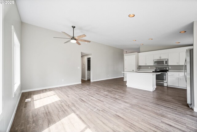 unfurnished living room with wood finished floors, baseboards, ceiling fan, and lofted ceiling